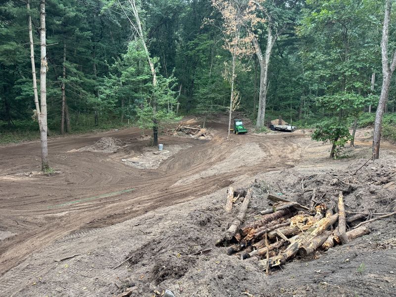 Cleared and graded wooded lot with stacked logs, land clearing project in Holmen, Wisconsin